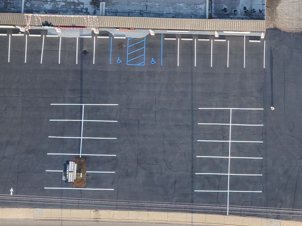 Aerial view of an empty parking lot with marked spaces and accessible parking area.