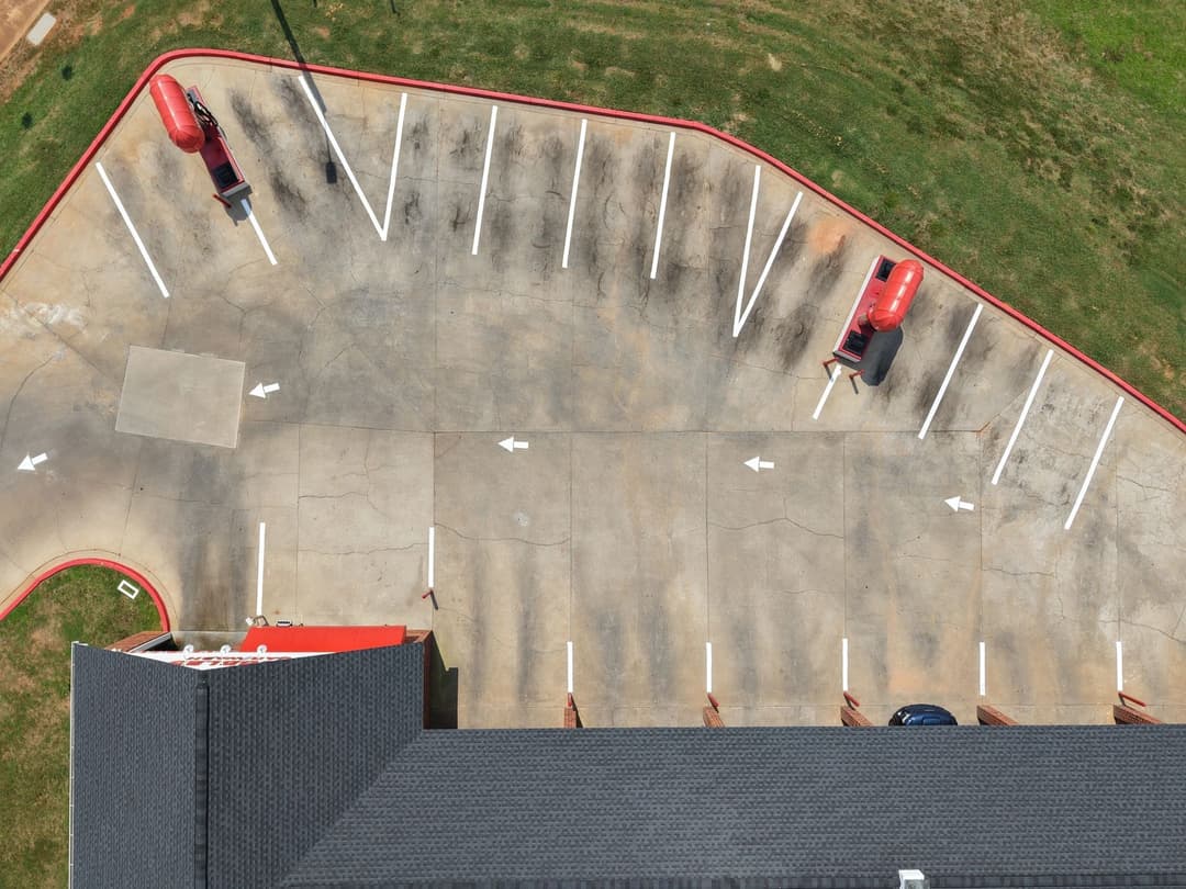 Aerial view of a parking lot with marked spaces and two red vehicles.