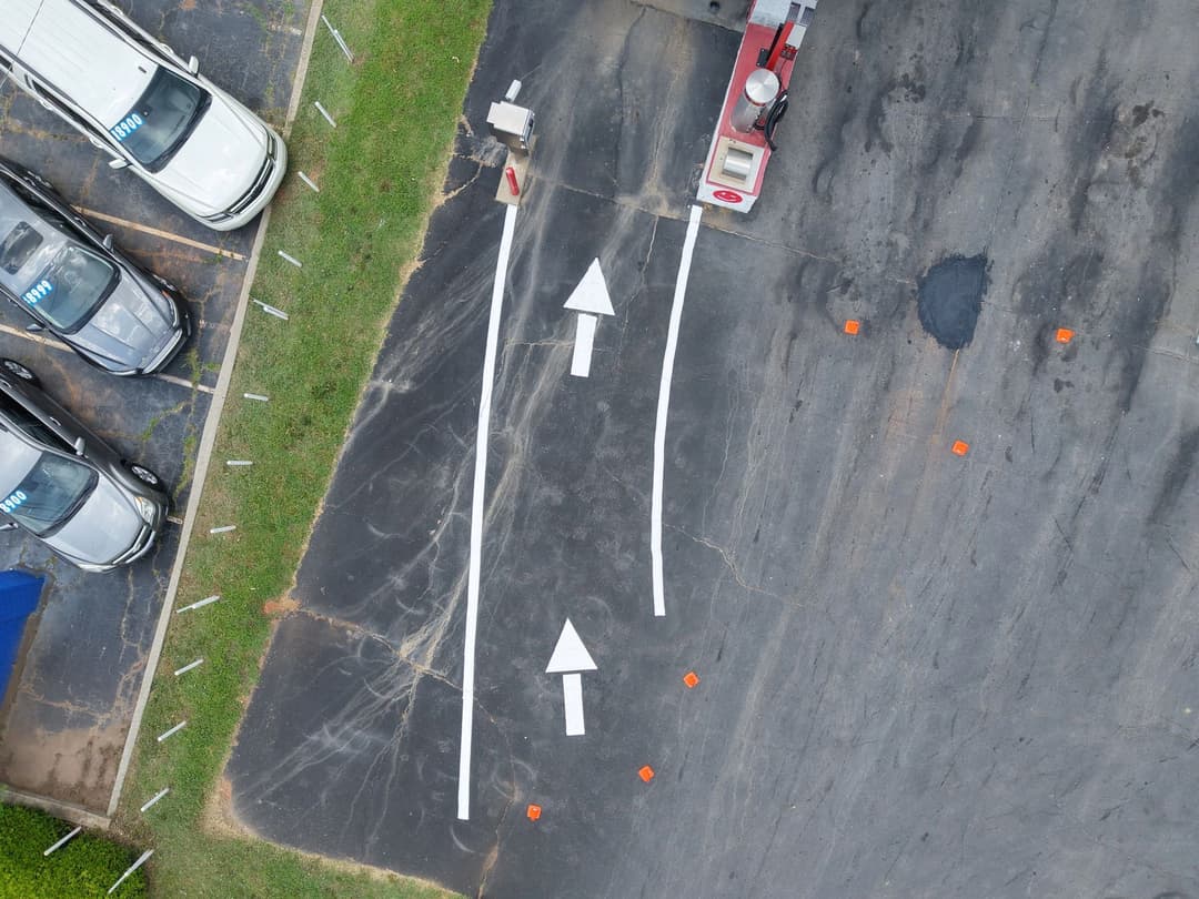 Aerial view of a parking lot with directional arrows and parked cars.