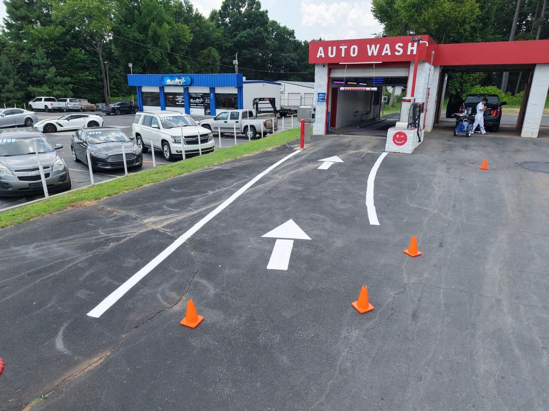 Auto wash entrance with directional arrows and cones, surrounded by parked cars.
