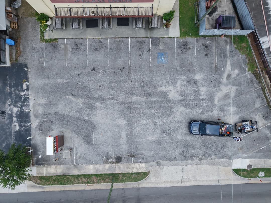 Aerial view of a nearly empty parking lot with a parked car near a building.