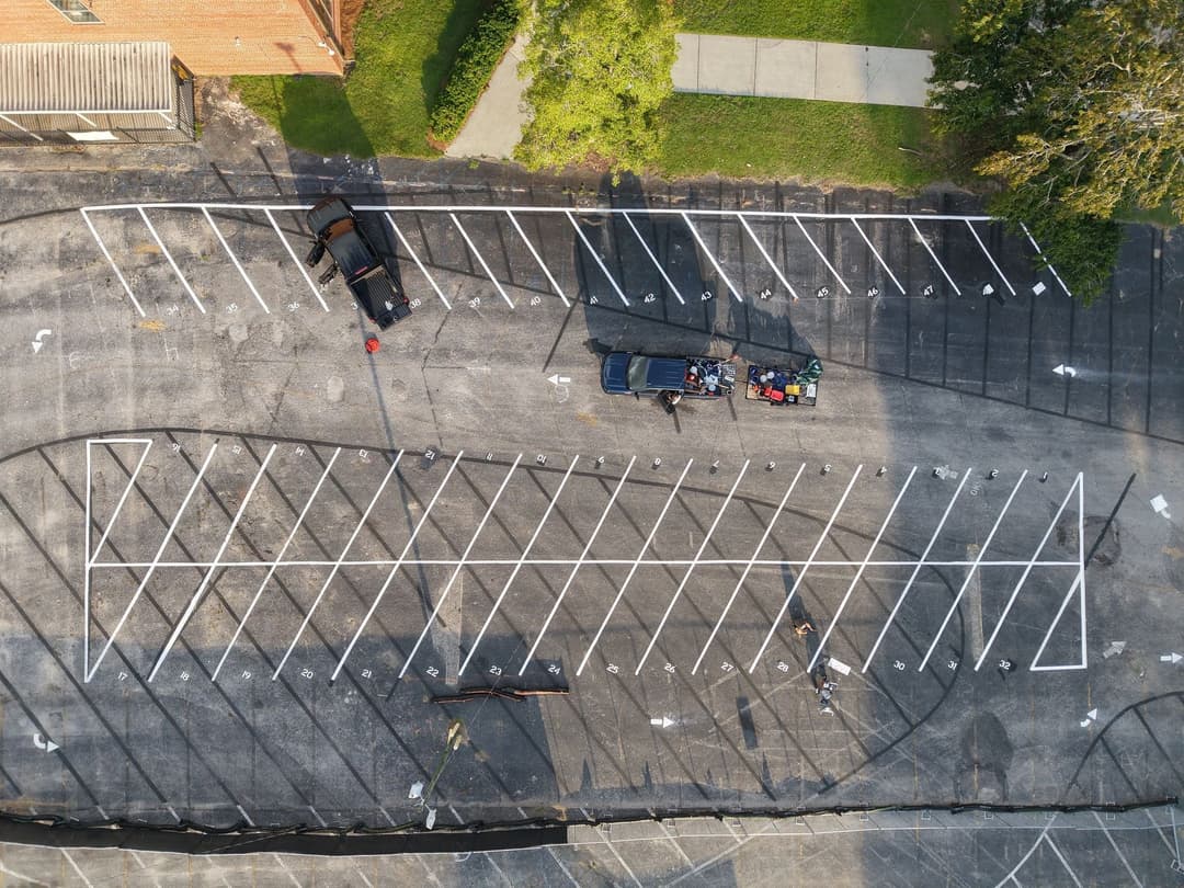 Aerial view of a parking lot with marked spaces and a truck loading supplies.