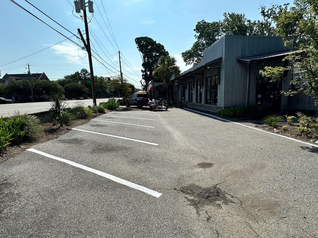 Empty parking lot with trees and a building in daylight, showcasing urban landscape.