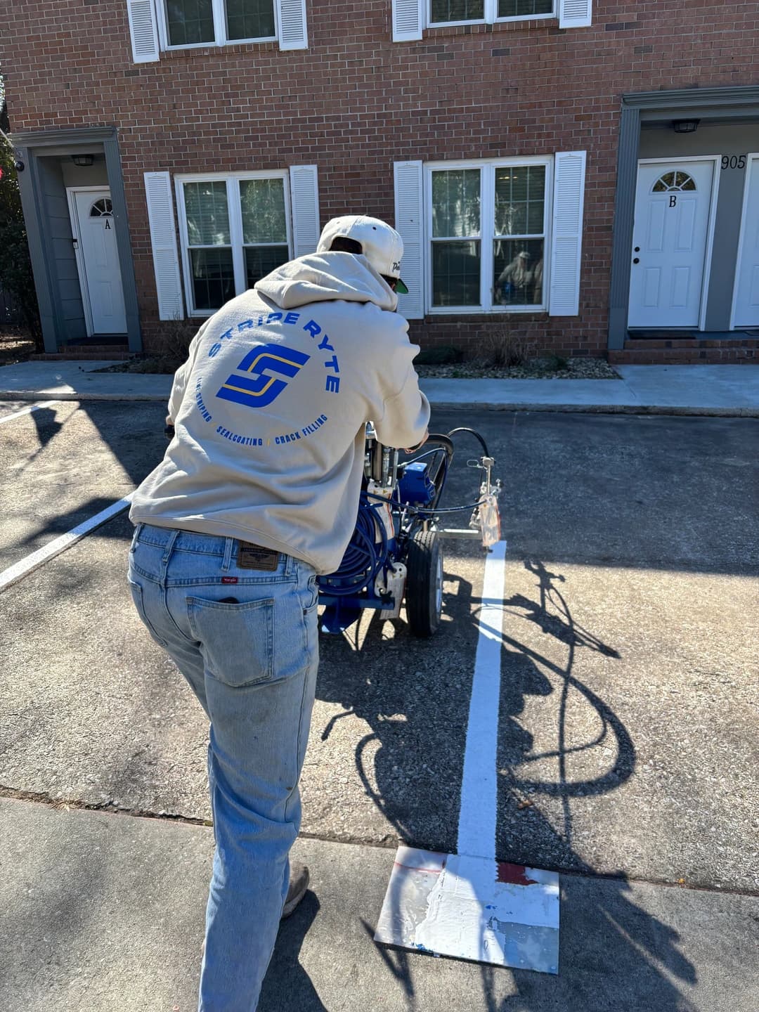 Person operating a pavement striping machine in a residential parking lot.