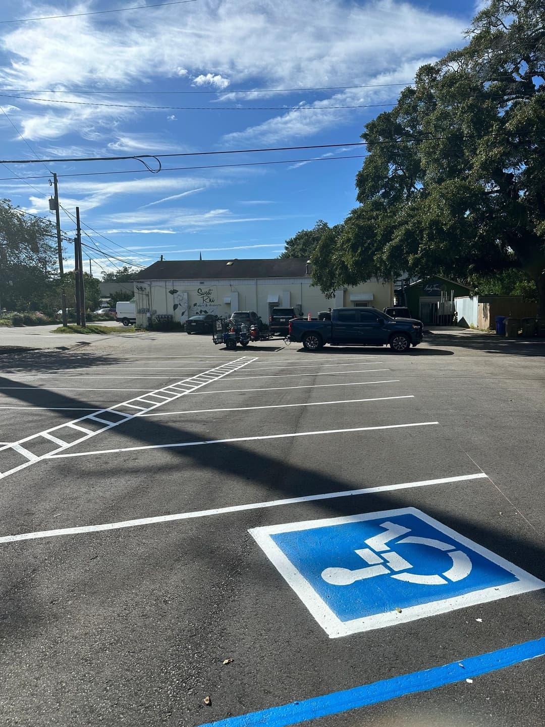 Accessible parking space in a lot with blue sky and vehicles in the background.